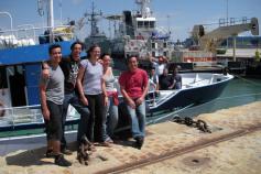 Foto de familia al finalizar la primera parte de la campaña. Los científicos en el muelle, los tripulantes a bordo del barco en el momento de salir a la mar camino de Huelva ©IEO
